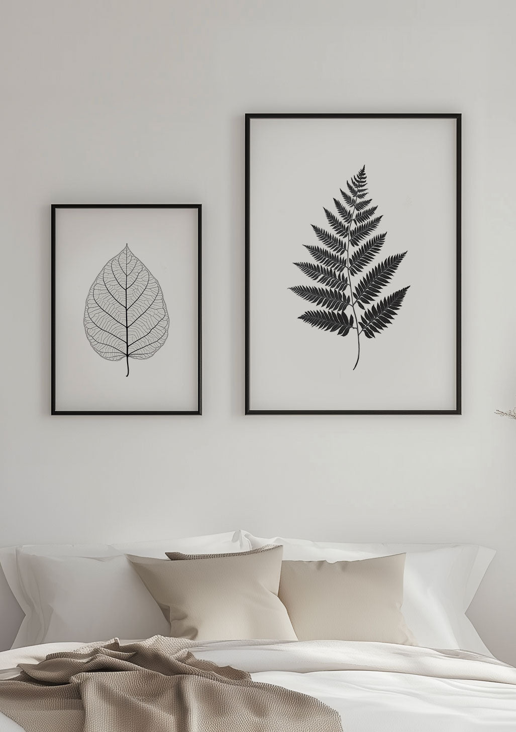 Deux affiches florales en noir et blanc encadrées au dessus d'un lit.