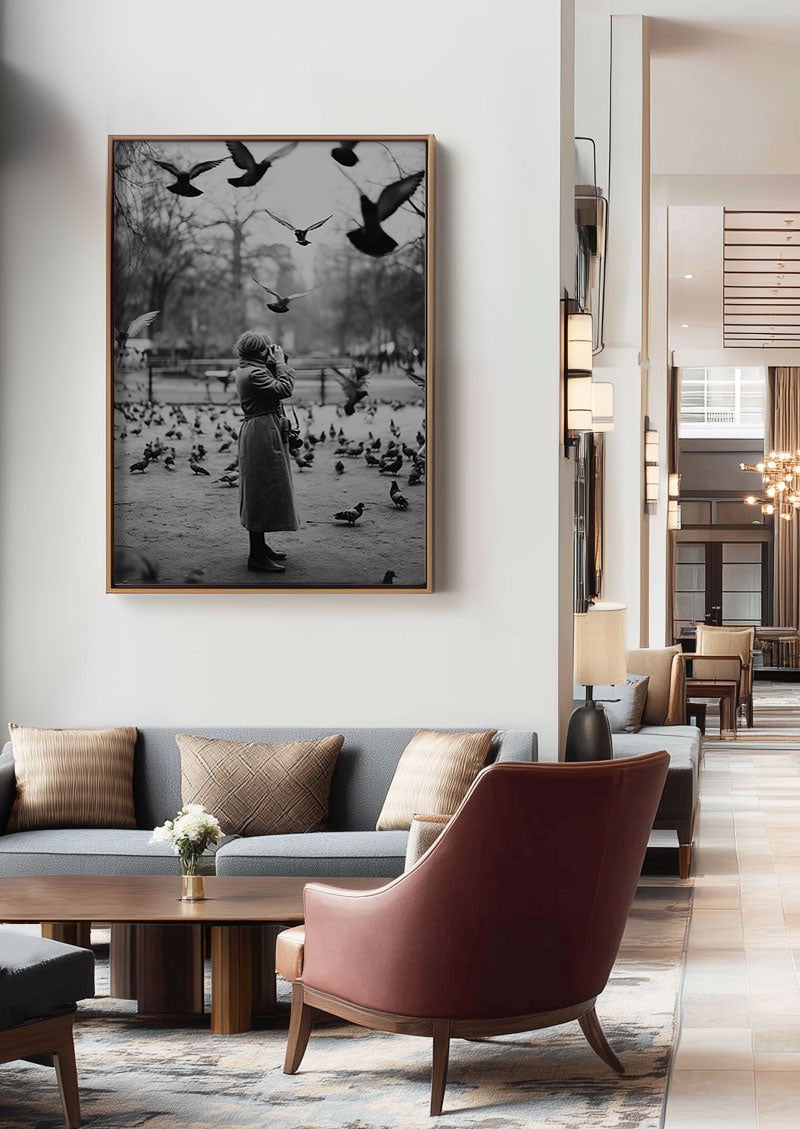 poster photo noir et blanc d'une dame et des pigeons encadrée au dessus d'un canapé dans un hall