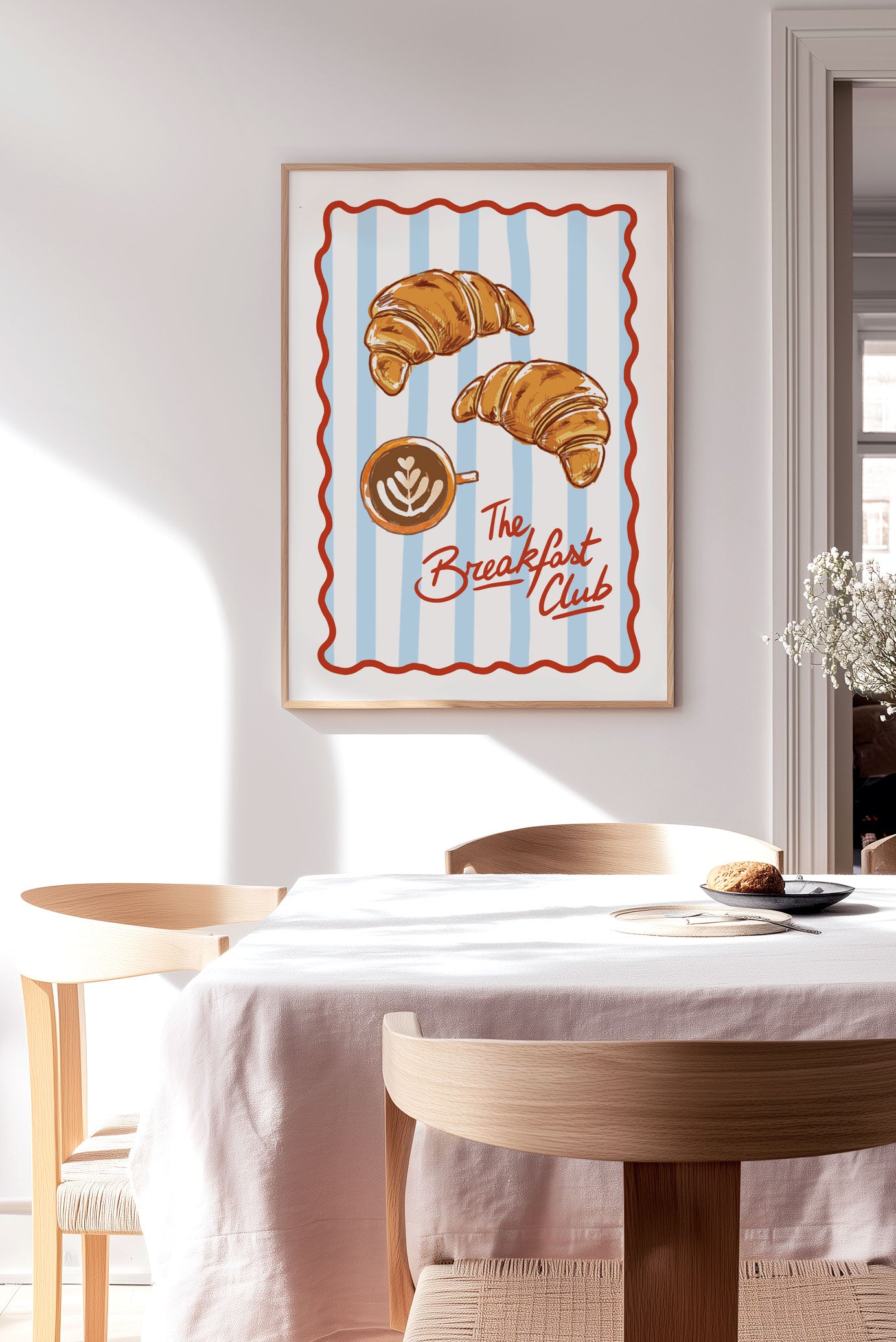 Affiche cuisine "the breakfast club" illustrant des croissants et un café, sur un mur