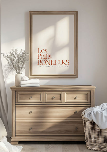 Affiche automne avec texte marron "les petits bonheurs" encadrée au dessus d'une commode
