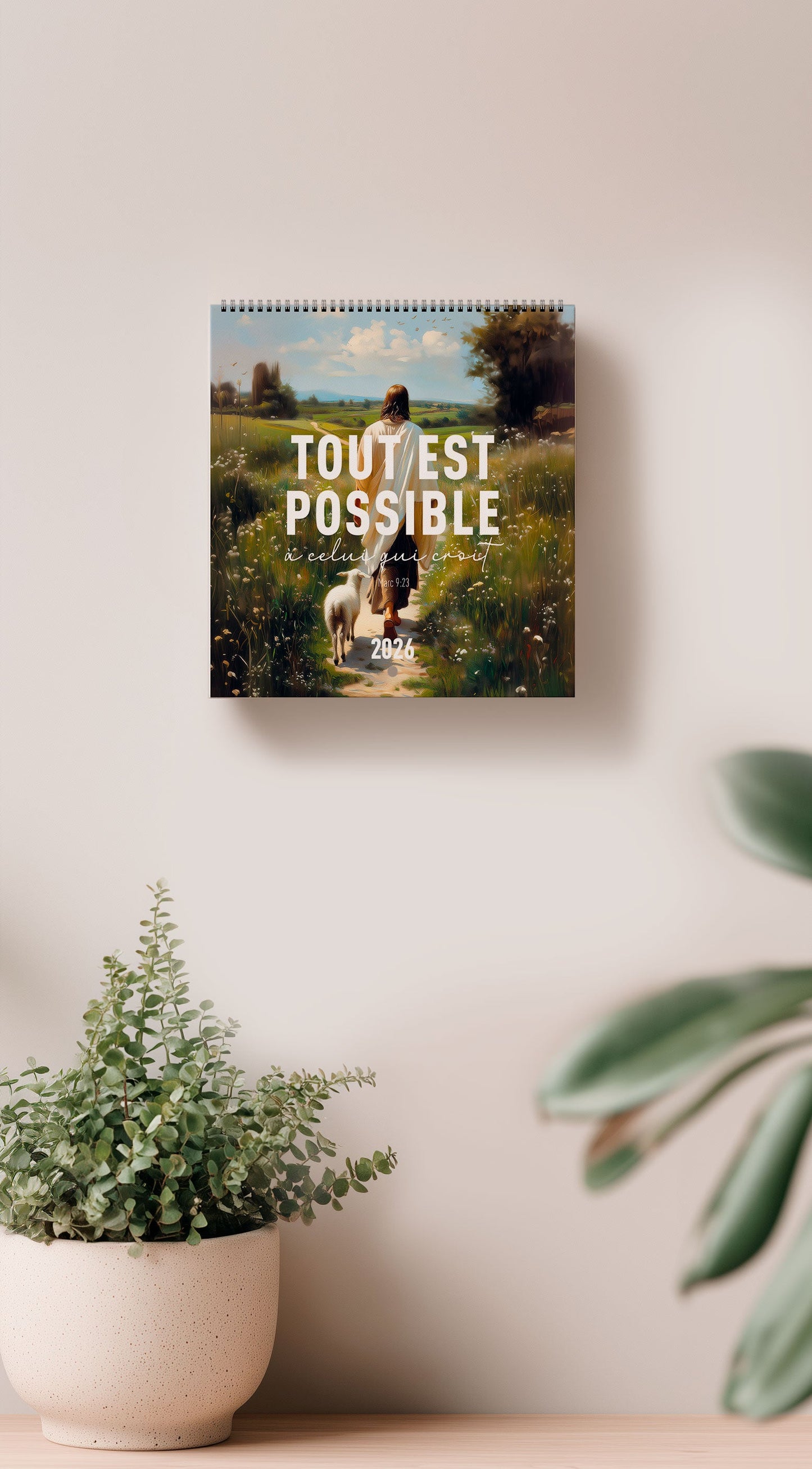 Calendrier chrétien 2026 mis en scène sur un mur, montrant la couverture avec jésus et un verset