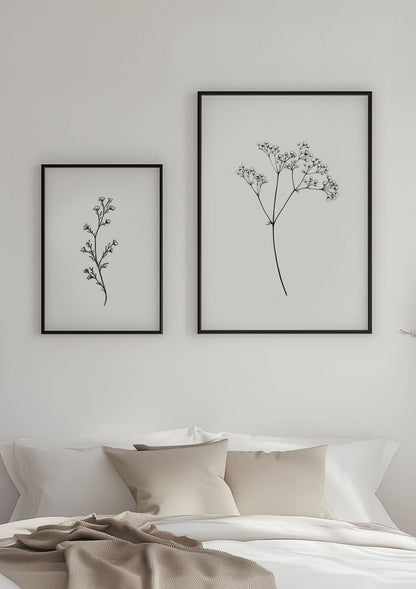 Deux affiches branches de fleurs encadrées sur un mur blanc.