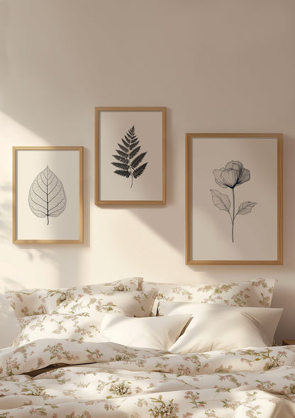 Trio d'affiches florales noir et blanc au dessus d'un lit.