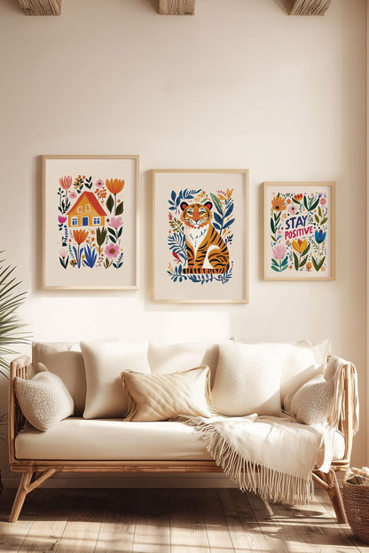 Trio d'affiches folk art maison, tigre, et "stay positive" encadrées sur le mur d'un salon